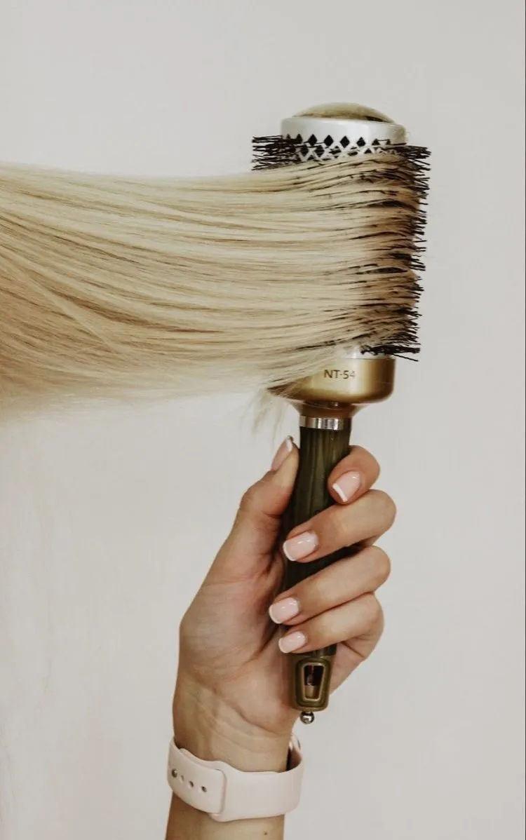 Hand holding a large round hairbrush
