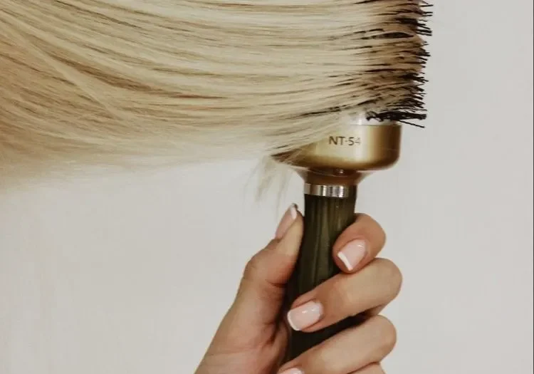 Hand holding a large round hairbrush