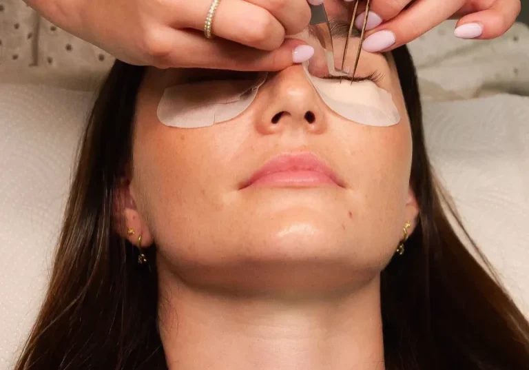 Woman receiving eyelash extensions with under-eye pads